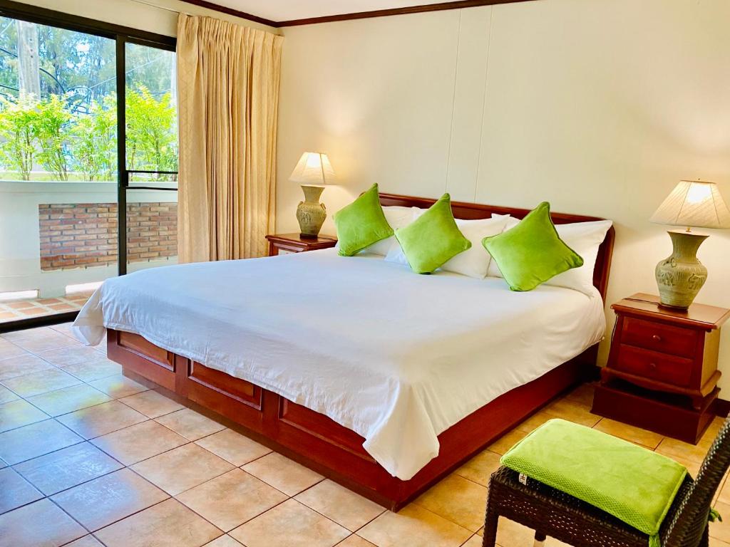 苏林海滩苏林湾旅馆的一间卧室配有一张带绿色枕头的大床