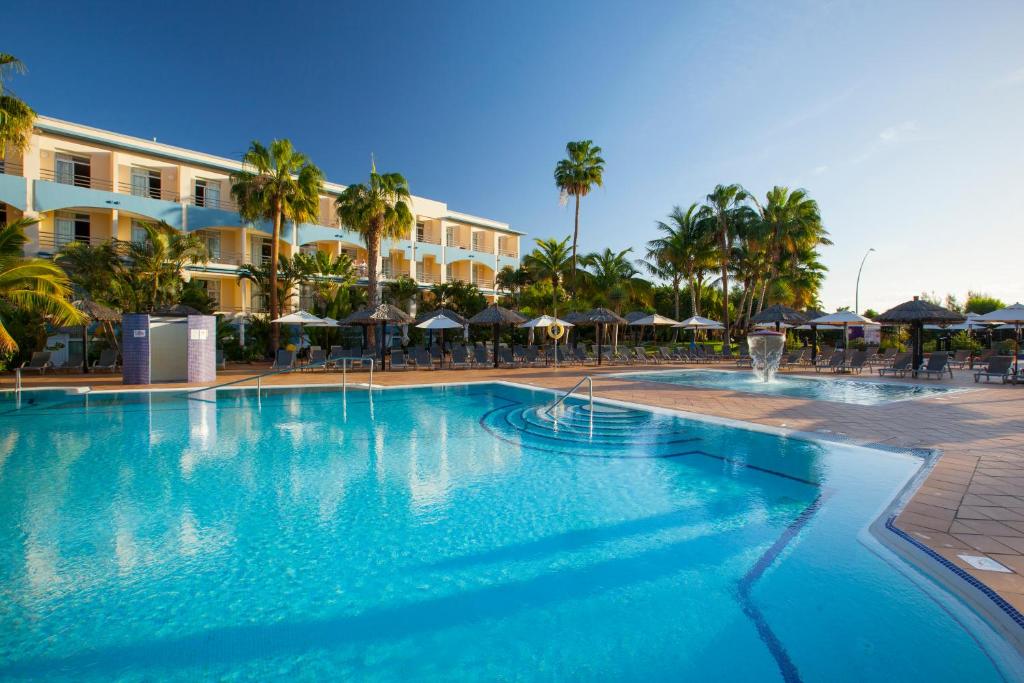 莫罗德哈布雷IFA Altamarena by Lopesan Hotels的棕榈树和遮阳伞度假村内的游泳池