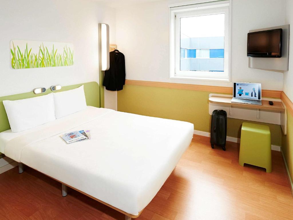 马尼塞斯瓦伦西亚机场宜必思快捷酒店的卧室配有白色的床和一张书桌上的笔记本电脑