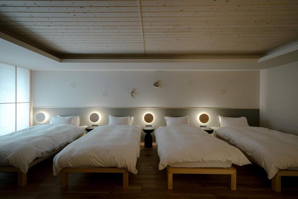 金泽so, KANAZAWA的配有白色床单和灯的客房内的三张床