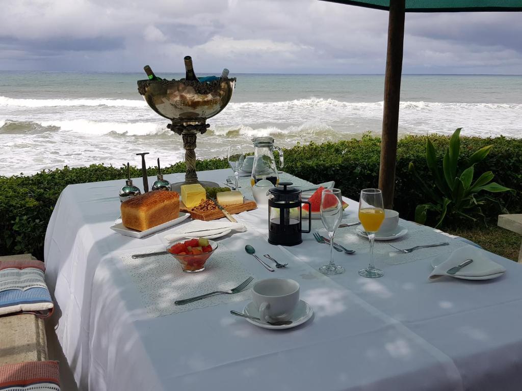 谢丽海滩Tropical Beach Boutique Guesthouse的海滩上的餐桌,包括食物和饮料