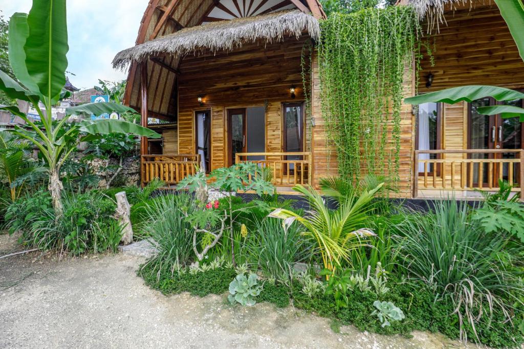 珀尼达岛Indah Guest House Nusa Penida的前面有植物的小木屋