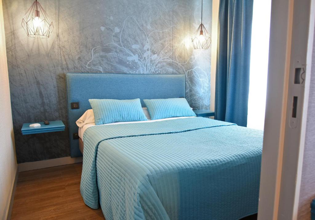 ViarmesAuberge la Renaissance的一间卧室配有蓝色的床和两个枕头