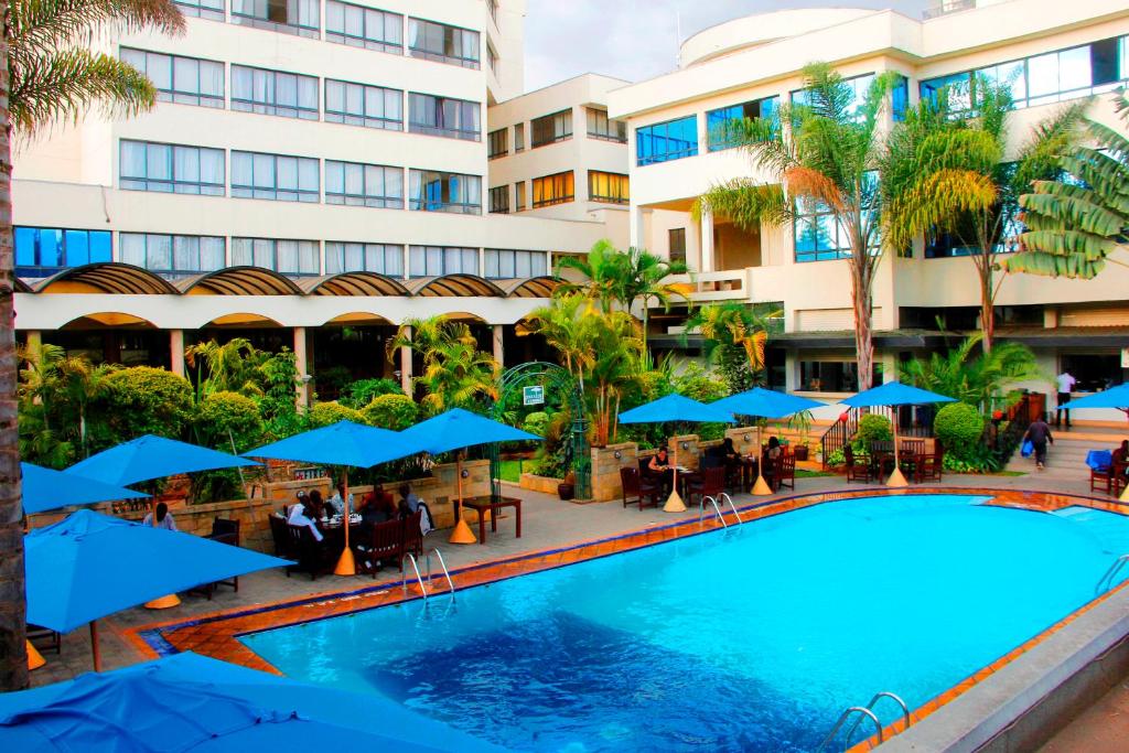 纳库鲁Merica Hotel的酒店前方的游泳池配有蓝色遮阳伞