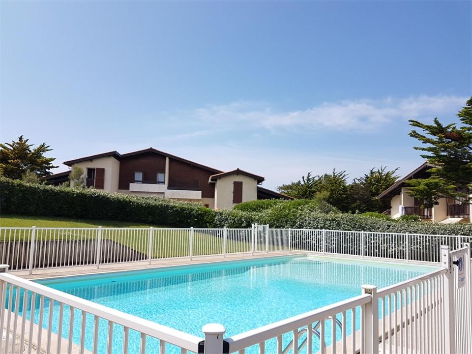 塞尼奥斯Réf 272,Seignosse océan, Villa Patio à 150m de la plage, avec place de parking et piscine commune , 4 personnes的游泳池周围设有白色围栏