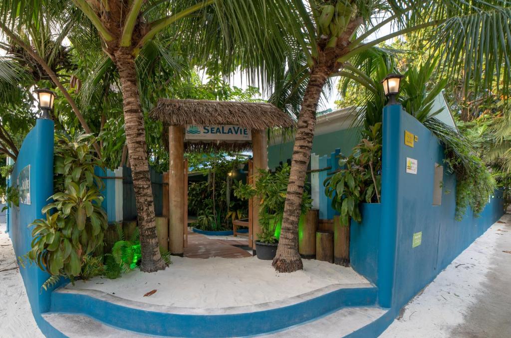 乌库拉斯SeaLaVie Inn的一座棕榈树度假村,位于一座建筑前