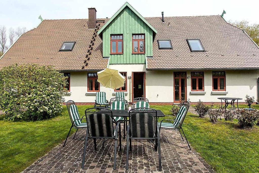 欧巴德伍斯图Ferienhaussiedlung Strandperlen Buchenhof 1b (Haustyp VI)的桌椅和遮阳伞位于房子前