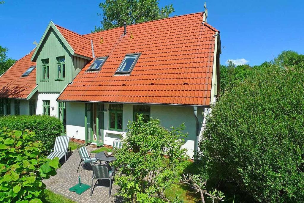 欧巴德伍斯图Ferienhaussiedlung Strandperlen Sanddornhof 3d (Typ I)的绿色房子,带橙色屋顶和椅子