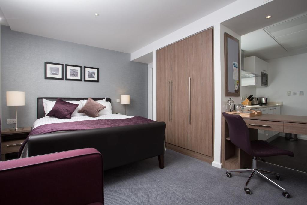 伯明翰伯明翰斯泰布里奇套房酒店的一间卧室配有一张床、一张书桌和一张书桌