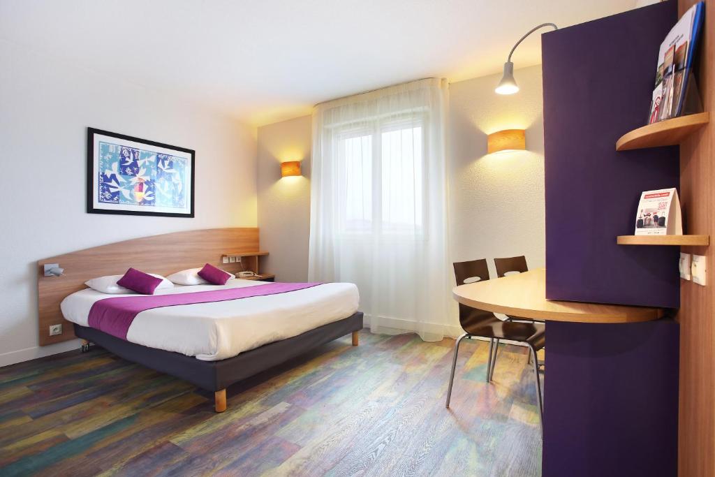 萨兰Suite-Home Orléans-Saran的酒店客房配有一张床铺和一张桌子。
