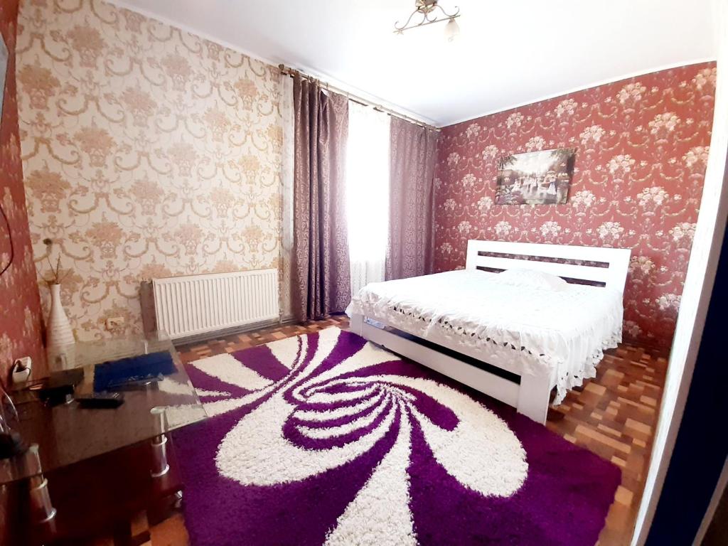 克洛佩夫尼茨基Yanovskogo 3k的卧室配有白色的床和紫色地毯。
