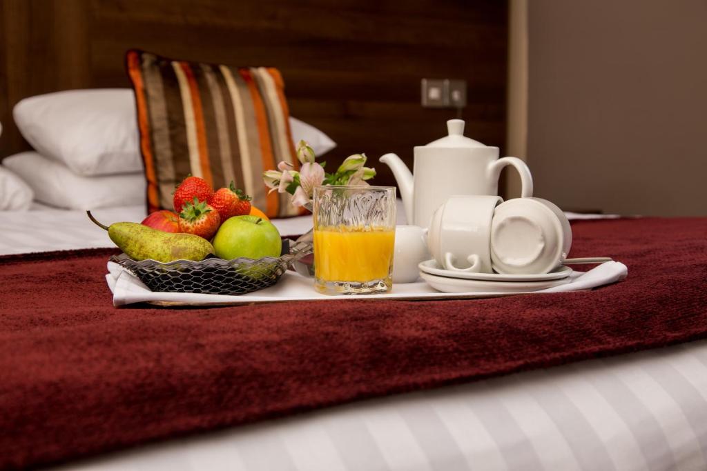 盖茨黑德The Gibside Hotel的床上的早餐托盘,包括水果和果汁