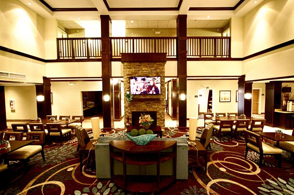 迈诺特迈诺特驻桥套房假日酒店的酒店大堂设有壁炉和桌椅