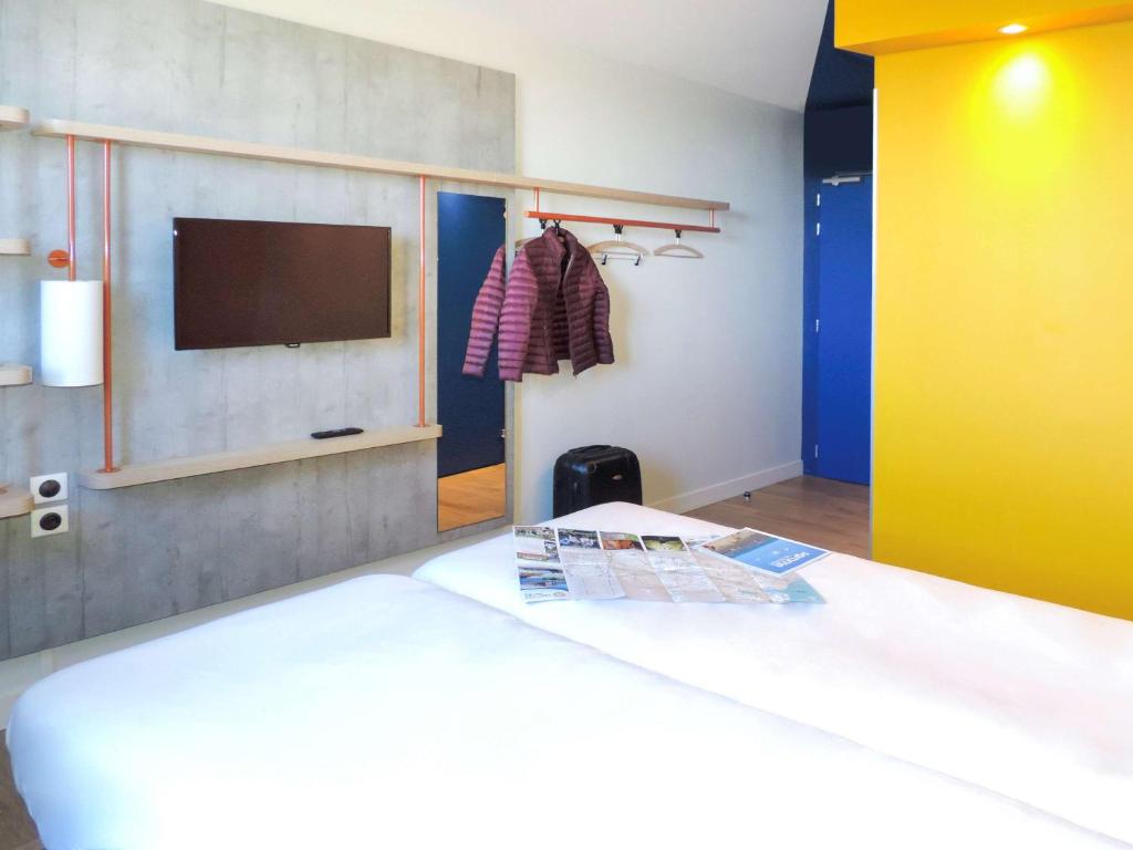 雅芳阿翁枫丹白露宜必思快捷酒店的一间卧室配有一张床,墙上配有电视