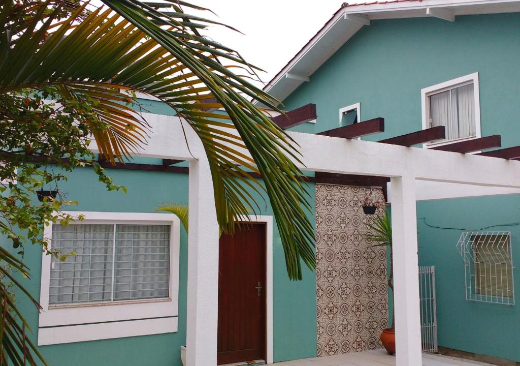 弗洛里亚诺波利斯Casa Açores Residencial - Apartamentos Praia dos Ingleses Floripa SC的蓝色的房子,有红色的门和棕榈树