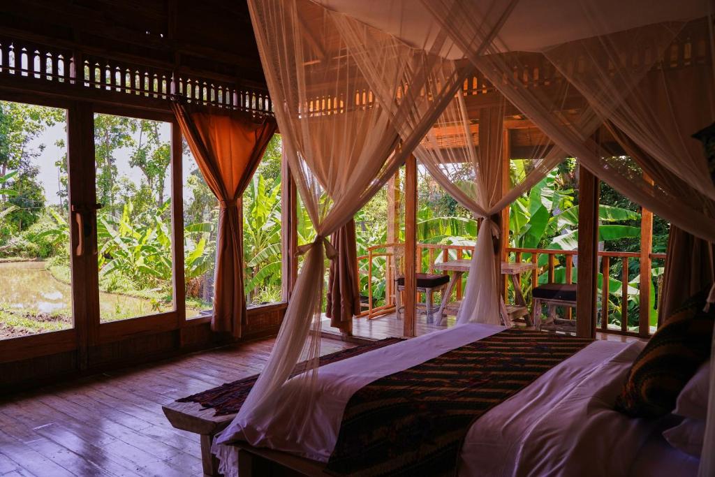 乌布Kidem Ubud Villas的一间卧室配有一张带窗帘和窗户的床。