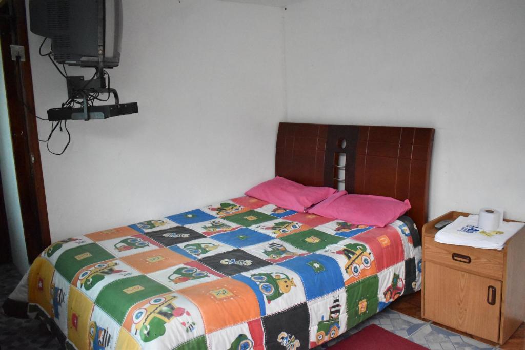PujilíEl Aliso - Pujilí的一间卧室配有一张带五颜六色棉被的床