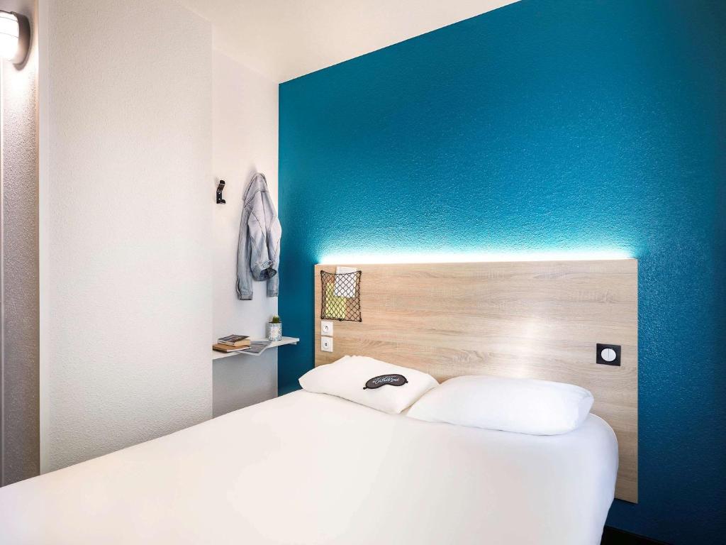 圣艾蒂安迪鲁夫赖hotelF1 Rouen Zénith Parc Expo的蓝色墙壁的房间里一张白色的床
