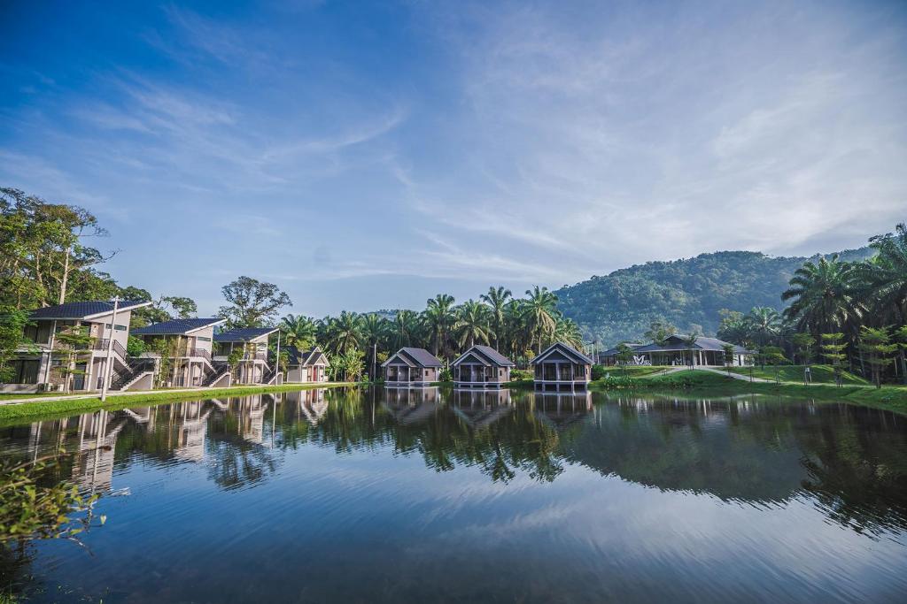 务边Sementra Hot Spring Nature Resort的水边一排树木的房屋