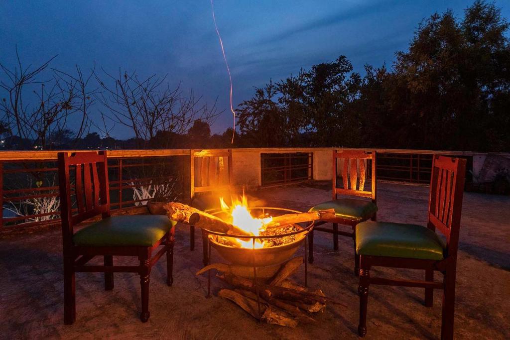 兰纳加The Rangers Lodge, Imran's Jungle Home in Corbett的火坑,带椅子和一张桌子,火炉