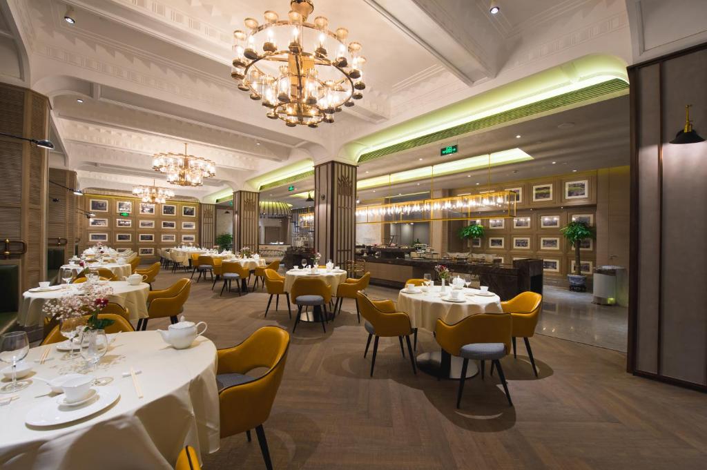 上海锦江都城经典上海南京饭店的餐厅配有白色的桌椅和吊灯