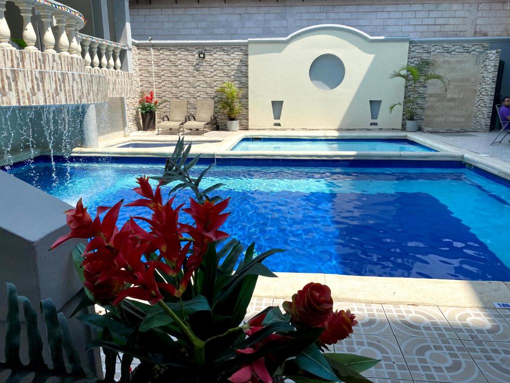 巴兰基亚Hotel Puerta de Oro的旁边是一个蓝色的海水和红色的鲜花的游泳池