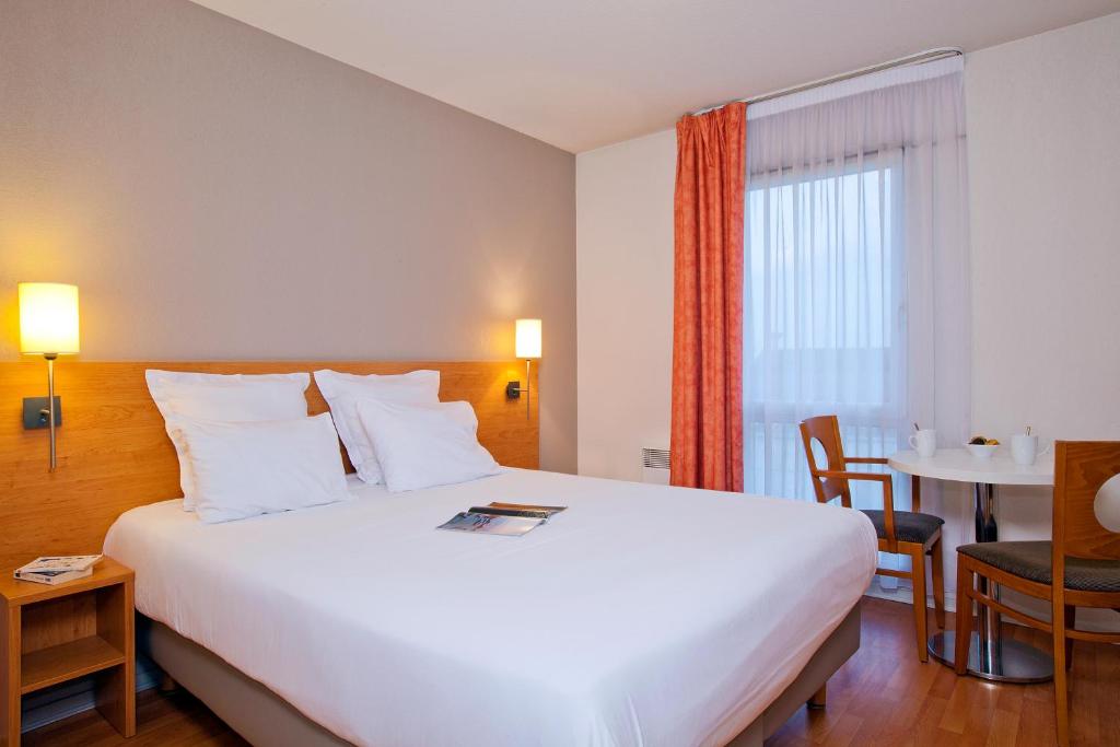 南特南特伯瑞赫塞祖尔阿菲尔酒店的酒店客房设有一张白色大床和一张桌子。