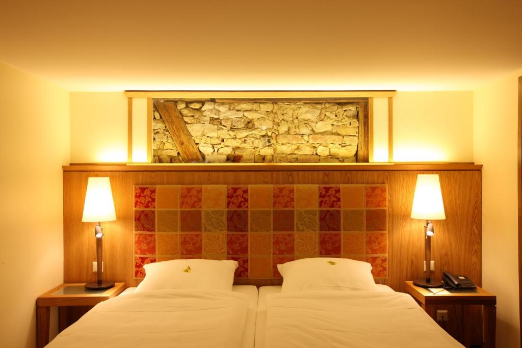 RammingenLandgasthof Adler的一间卧室配有一张带两个枕头和两个灯的床。