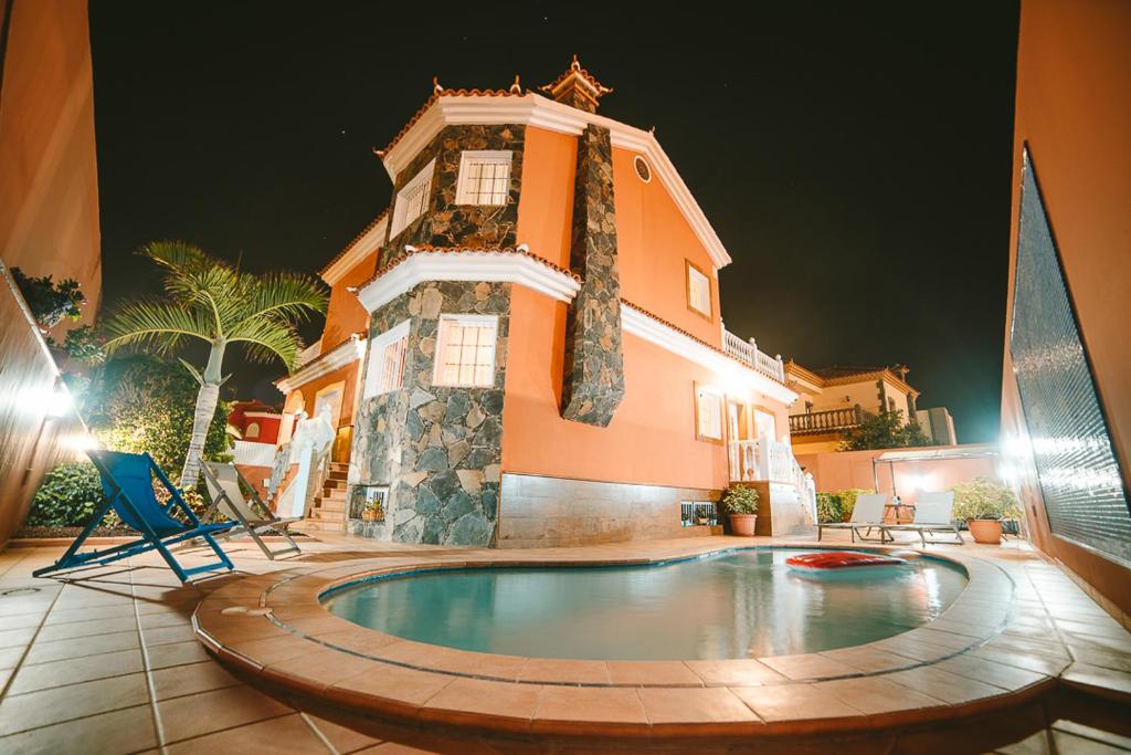 马斯帕洛马斯Villa Morada Sonneland con piscina privada climatizada的大楼前带游泳池的房子