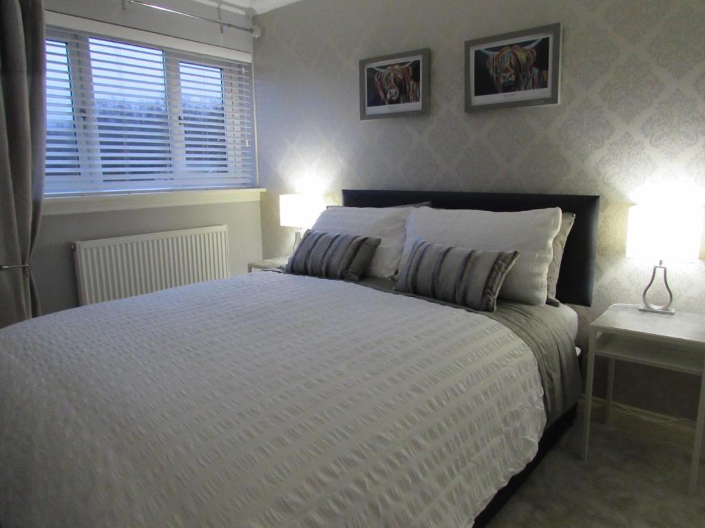 巴洛赫Levenview Holiday Apartment Loch Lom的一间卧室配有一张带两盏灯的床和一扇窗户。