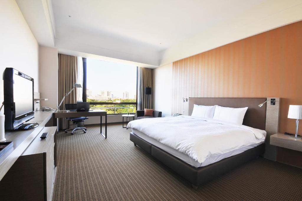 台南Academy Hotel的酒店客房配有一张床、一张书桌和一台电视。