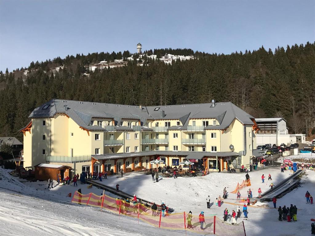 费尔德伯格Ferienwohnung Gipfelstürmer Feldberg - Ski in Ski out, Whirlpool & Infrarotkabine的一座大建筑,里面有很多人下雪