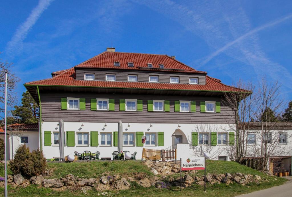 阿尔布斯塔特Höhengasthof Wanderheim Nägelehaus的一座大型房屋,设有红色屋顶和绿色百叶窗