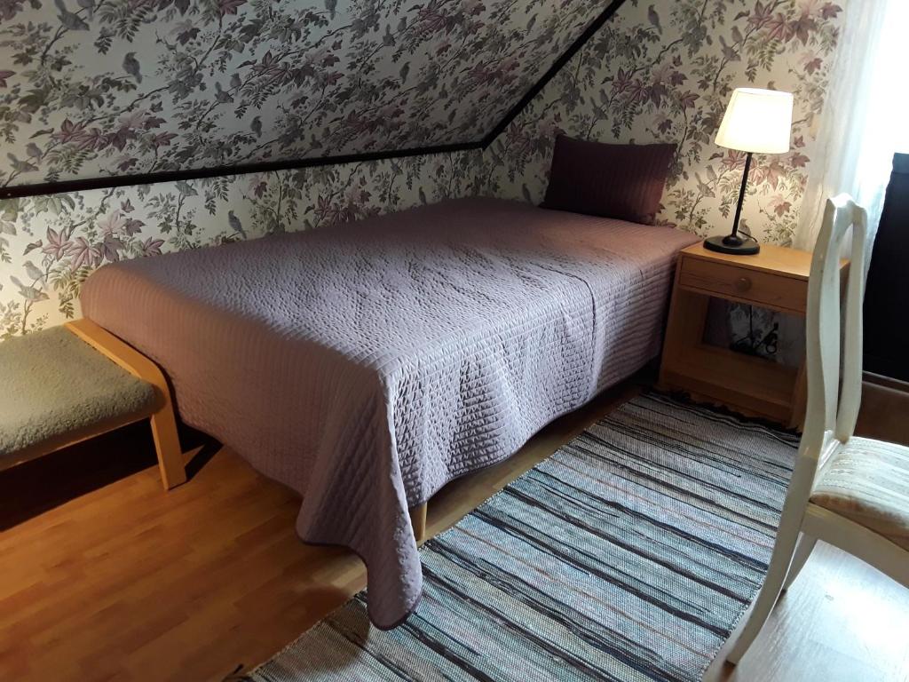 乌普萨拉Naturnära enkel rum B&B i Uppsala Ramstalund的一间卧室配有一张床、一盏灯和一把椅子