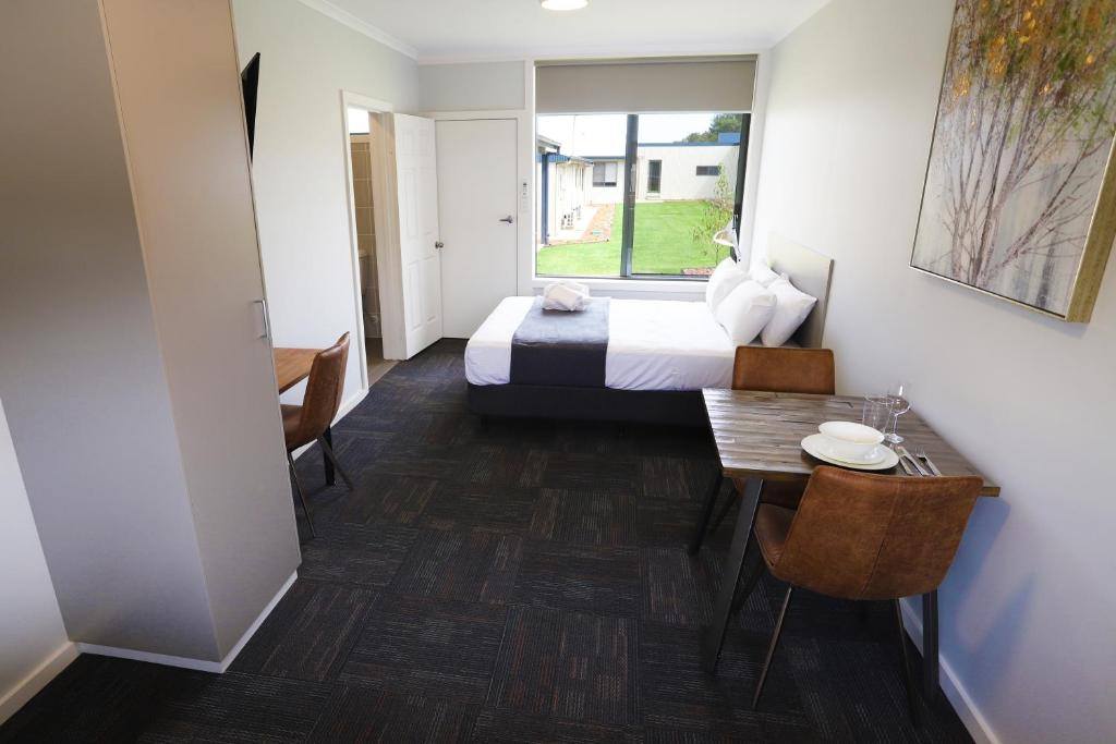 达博Eastend Studio Apartments的酒店客房设有床、桌子和窗户。