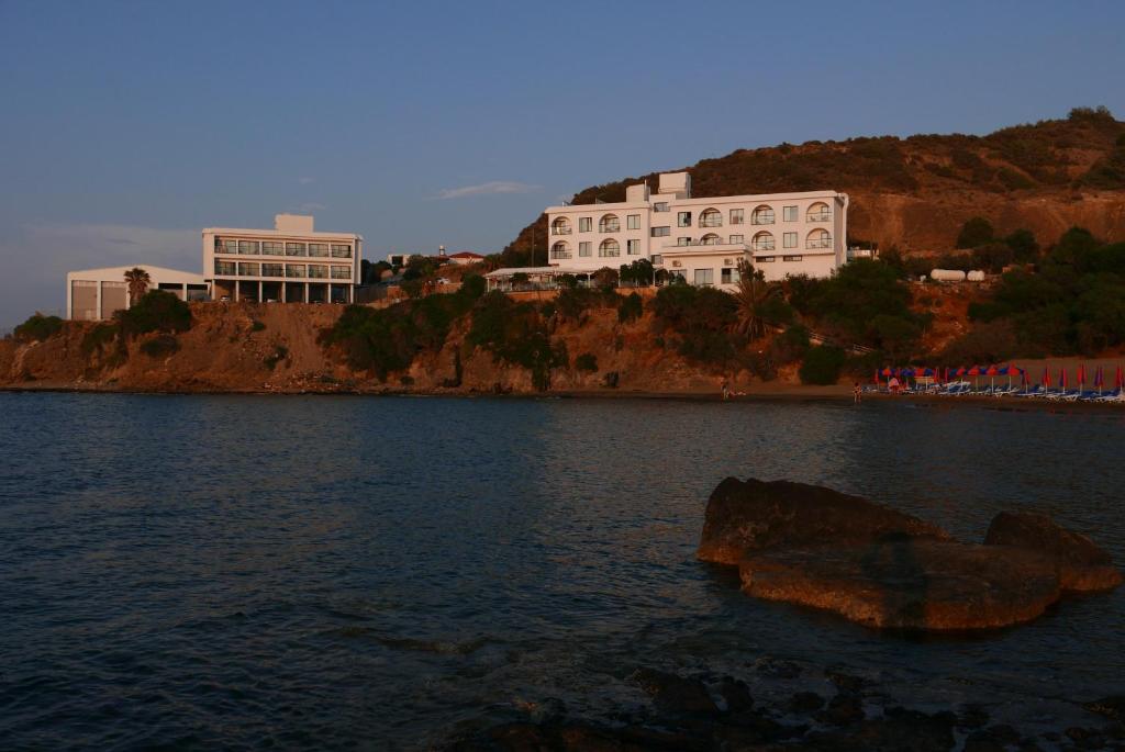 下皮尔戈斯E.J. Pyrgos Bay Hotel的一座大建筑,位于山顶上,靠近水体