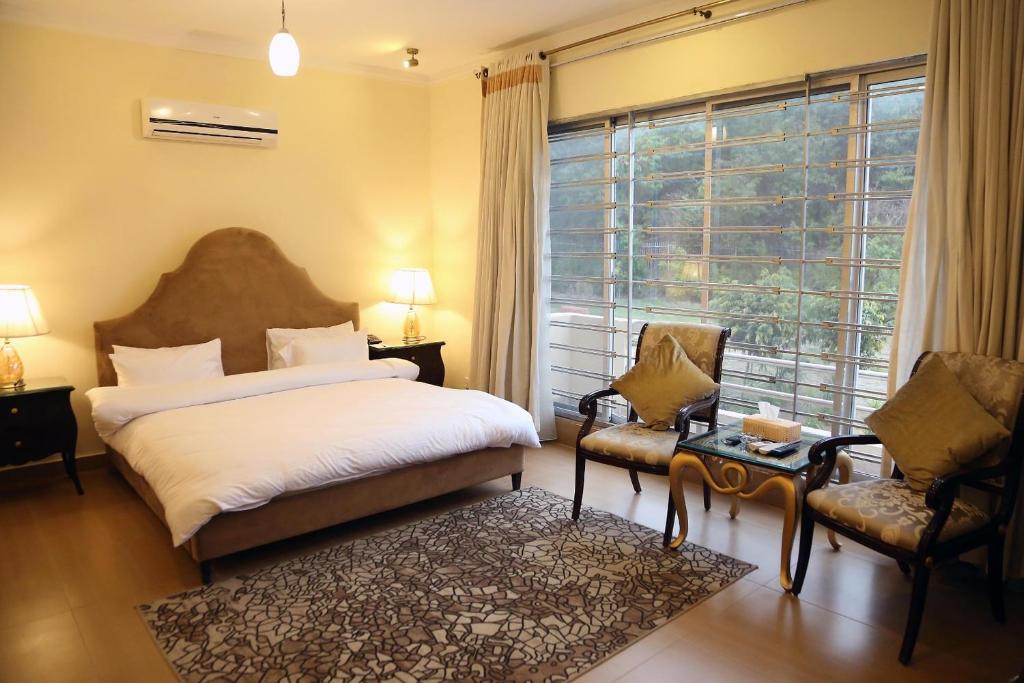 拉瓦尔品第Butterfly Guest House Phase 7 Bahria Town的卧室配有床、椅子和窗户。
