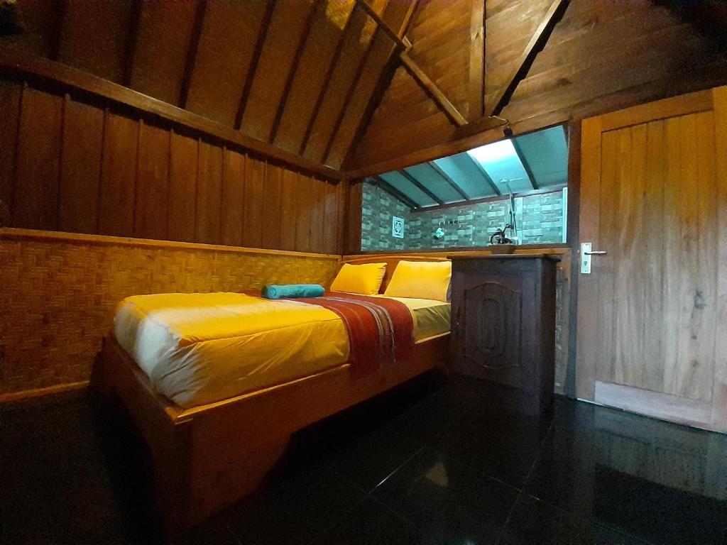 特特巴图Tetebatu Valley Bungalows的木制客房内的一间卧室,配有一张床