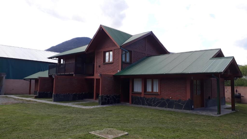 普埃洛湖Lago Puelo Departamentos Turisticos的绿色屋顶的棕色砖屋