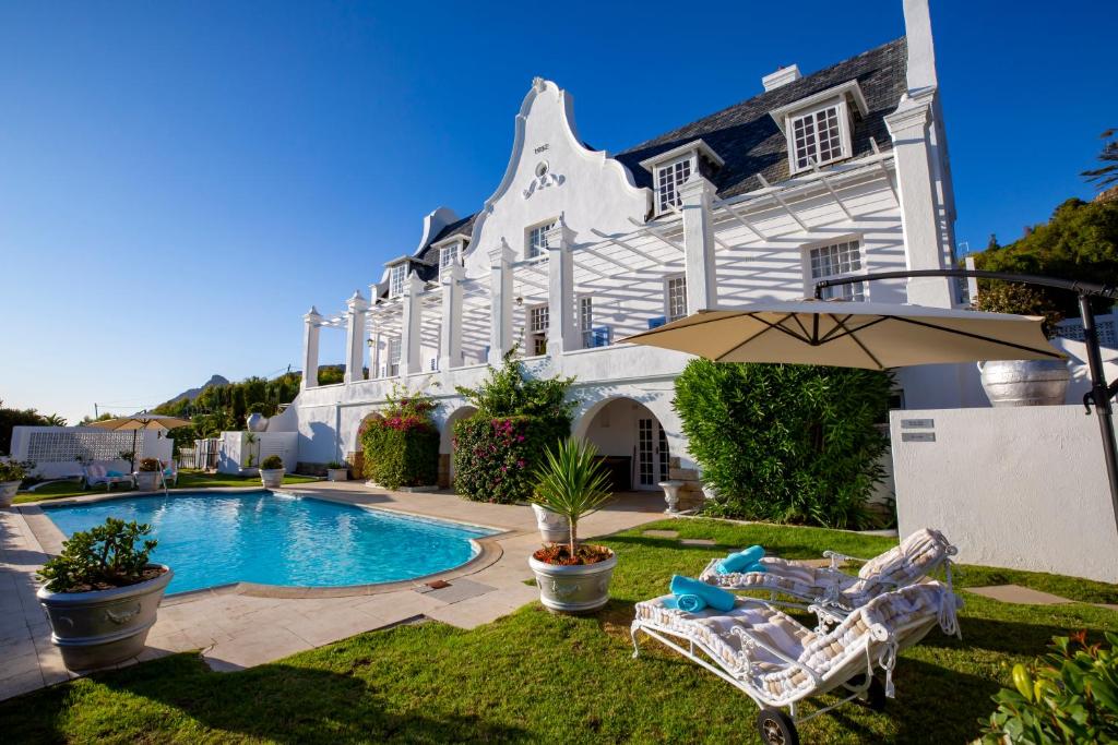 康斯坦提亚Stillness Manor Estate & Spa的一座房子,设有游泳池、两把椅子和一把遮阳伞