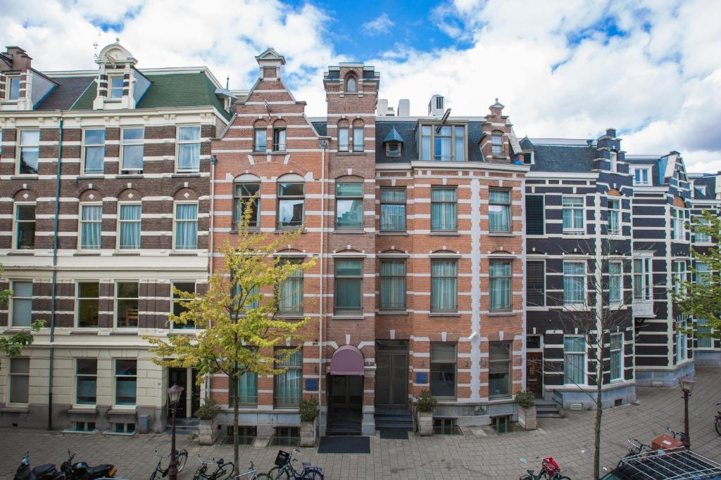 阿姆斯特丹罗默阿姆斯特丹酒店 的一座大型砖砌建筑,前面停放着自行车