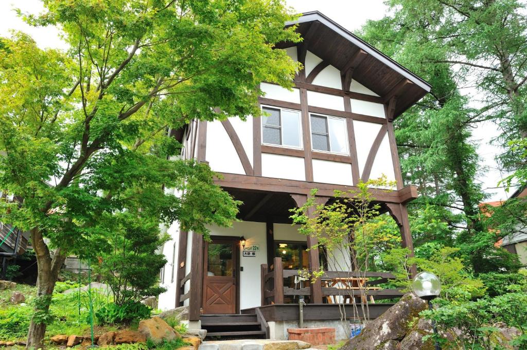 猪苗代町Cottage All Resort Service / Vacation STAY 8445的树林中的一个小房子,有围着门廊