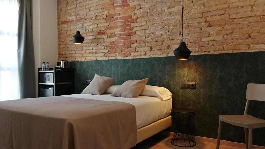 巴塞罗那坎东酒店的一间卧室设有一张床和砖墙
