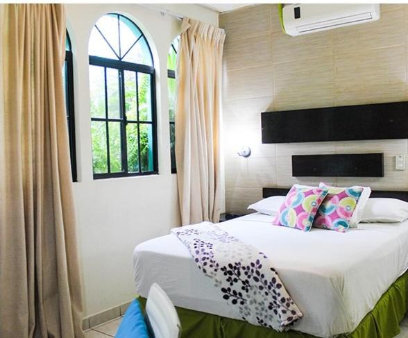 圣萨尔瓦多天使别墅酒店的卧室配有带枕头的床铺和窗户。