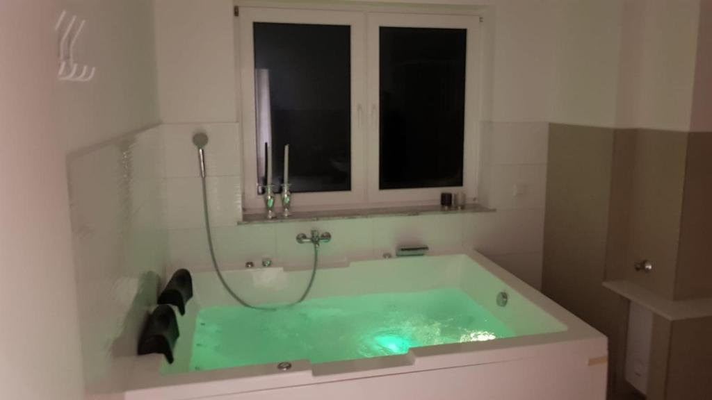 特罗斯多夫Luxuswohnung mit Jacuzzi Nähe Flughafen Köln/Bonn的带窗户的浴室内的绿色浴缸