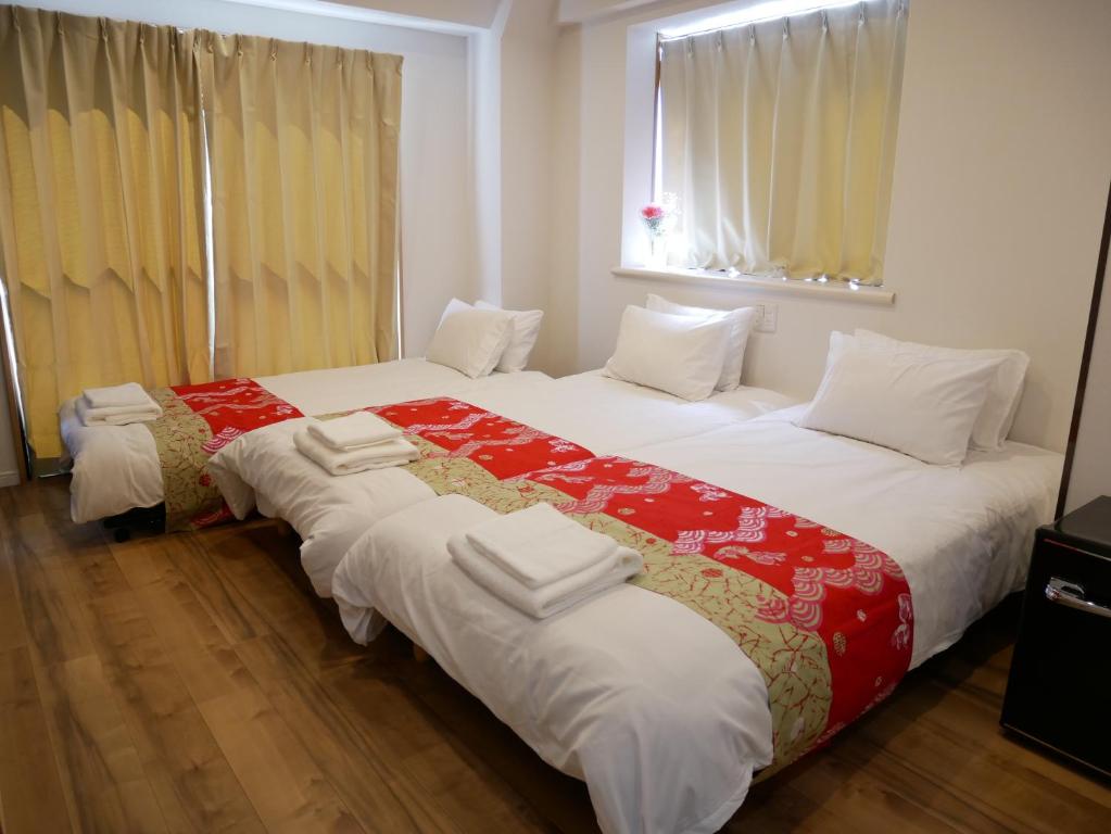 东京Tokyo shinjukutei Hotel Asahi gruop 東京新宿亭ホテル的配有2张位于酒店客房的床,提供白色和红色床单