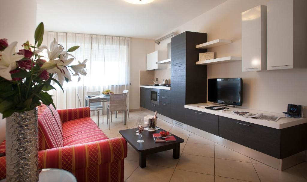 阿尔巴卡利萨诺公寓式酒店的一间带红色沙发的客厅和一间厨房