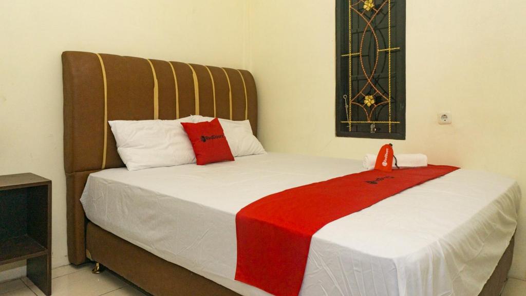 查亚普拉RedDoorz near Sentani Airport Jayapura的一间卧室配有一张床铺,床上铺有红色毯子