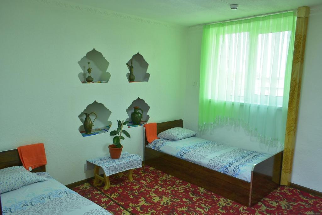 布哈拉Masturabonu Ravshan的一间卧室设有两张单人床和一个窗户。