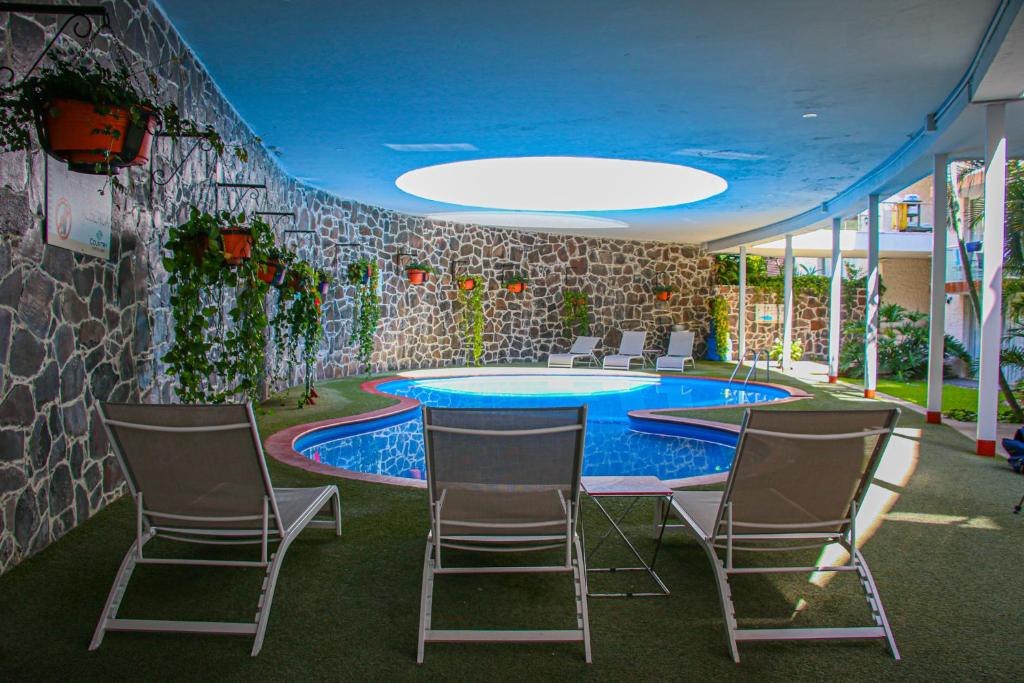 瓜达拉哈拉乡村酒店及套房的配有桌椅的房间和游泳池